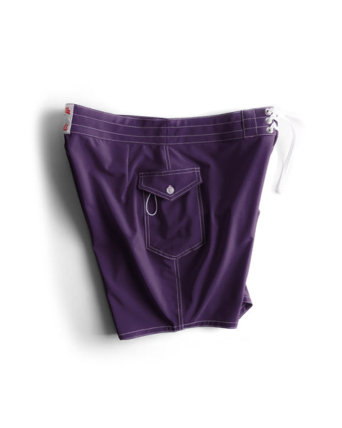 The 808 SurfStretch Side Pocket Boardshorts in purple feature white stitching, a side flap pocket, and white drawstrings at the waistband, shown against a white background.