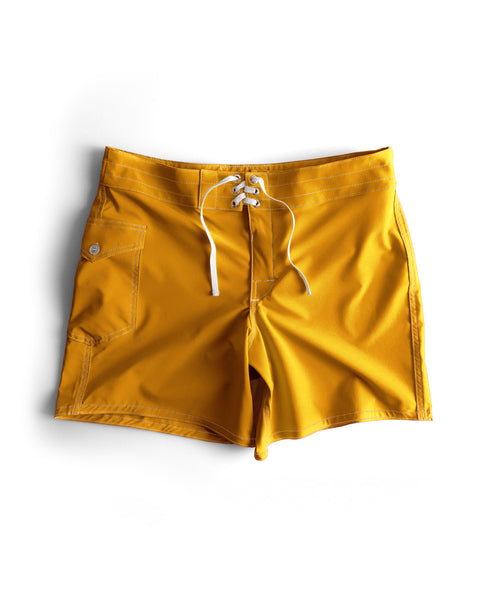 The 806 SurfStretch Side Pocket Boardshorts in gold feature white drawstrings, a side pocket, and white stitching, shown laid flat on a white background.