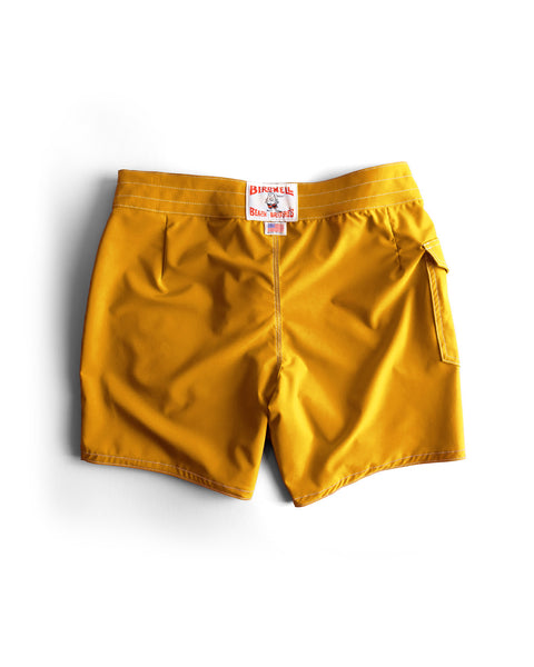 A pair of 806 SurfStretch Side Pocket Boardshorts in gold, featuring side and back pockets, is displayed flat on a white background, with a branded label visible on the waistband.