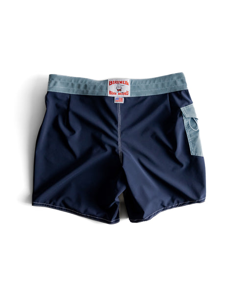 The 806 SurfStretch® Side Pocket Boardshorts in Navy/Federal Blue feature a light blue waistband, side pocket, and red and white Birdwell patch above the back pocket. Laid flat on a white background. Made in the USA for trusted quality.