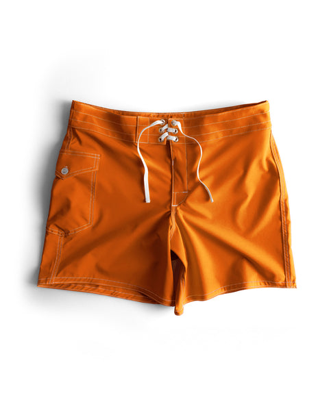 The 806 SurfStretch Side Pocket Boardshorts in medium orange feature white stitching, a lace-up front, side pocket with button, and a relaxed fit. Made in the USA for comfort and style, perfect for in or out of the water. Shown laid flat on white background.