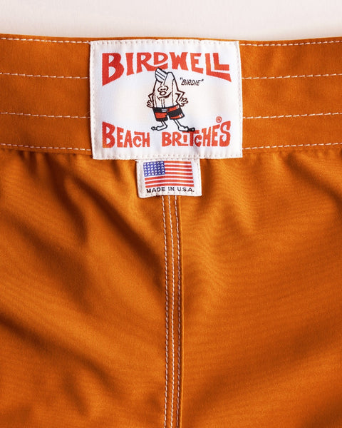 Close-up of the 806 SurfStretch Side Pocket Boardshorts in medium orange, featuring a white 