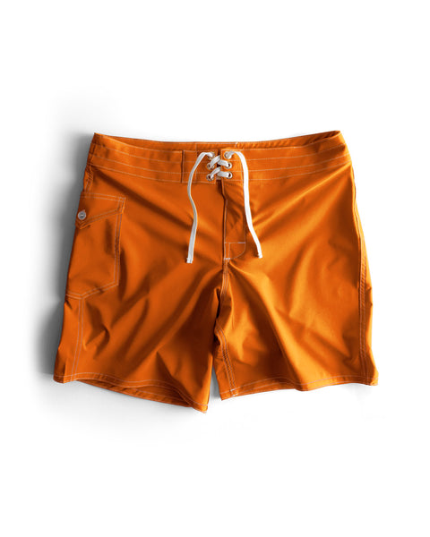 The 808 SurfStretch Side Pocket Boardshorts in medium orange feature a white lace-up drawstring, buttoned side pocket, and visible stitching. Made in the USA for comfort and style; shown laid flat on a white background.
