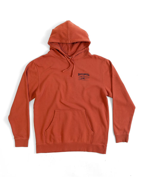The Bros Midweight Hoodie - Paprika features a relaxed fit, rust-colored pigment dye, front pocket, drawstrings, and a small Birdwell screen-print logo on the left chest. Shown laid flat on a white background.