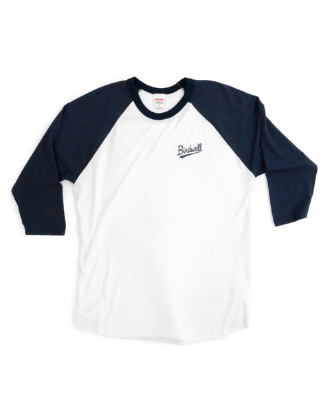 The Baller 3/4 Sleeve Raglan in White/Navy is a USA-made, garment-dyed t-shirt featuring navy 3/4-length raglan sleeves and a small Birdwell logo on the left chest, shown flat against a white background.