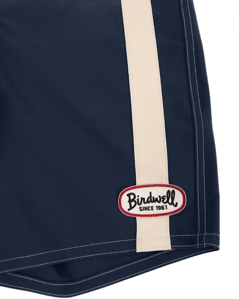 Close-up of the 808 Mono Stripe - Navy/Bone SurfStretch boardshorts featuring a vertical bone stripe and a red-bordered oval 