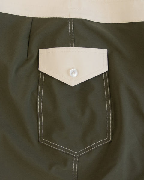 Close-up of the 808 Mono Stripe - Army/Bone: green SurfStretch fabric with a beige rectangular flap pocket, white stitching, and a central white button; proudly made in the USA.