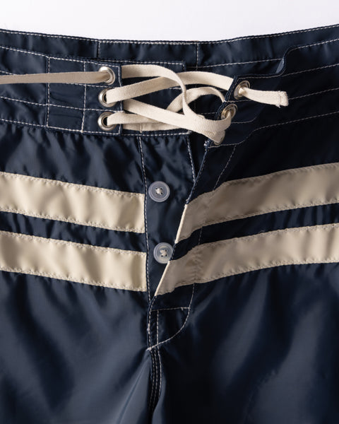 Close-up of the waistband of the 300 Comp Stripe - Navy/Bone boardshorts, showing two beige stripes, lace-up drawstring with metal eyelets, and button fly closure.