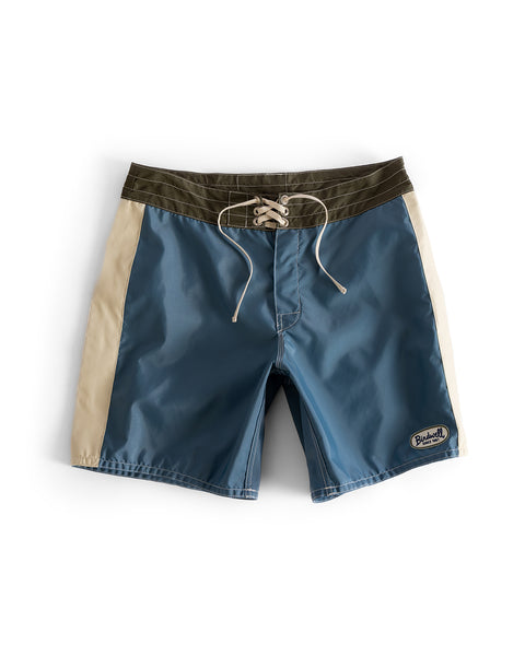 The 300 Legend boardshorts in Federal Blue feature beige side panels, a dark olive waistband, and a white drawstring. Made from quick-drying fabric with a small patch on the lower left leg, they are displayed flat on a white background.