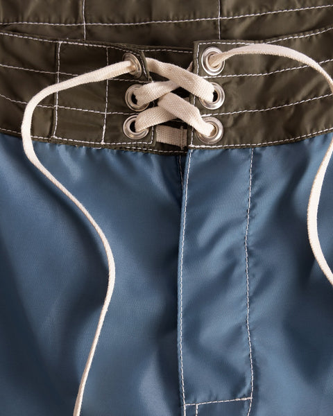 Close-up of the waistband on 300 Legend boardshorts in Federal Blue, Dark Olive, and Bone, featuring white laces through metal eyelets in a crisscross; quick-drying and proudly made in the USA.