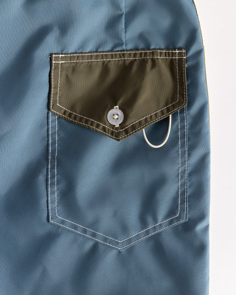 Close-up of the 300 Legend pocket in Federal Blue with Dark Olive flap and Bone button—classic SurfNyl boardshorts style, made in USA with quick-drying fabric.