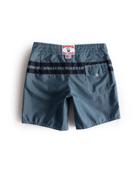 The 300 Comp Stripe - Federal Blue/Navy boardshorts feature black horizontal stripes on the back, a right-side buttoned back pocket, and a white BIRDWELL label with red text on the waistband. Proudly made in the USA.