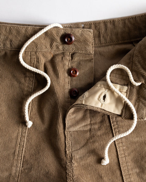 Close-up of Classic Corduroy Shorts - Acorn featuring an adjustable drawcord waist, three brown buttons, and a partially open fly revealing beige inner fabric with a buttonhole.