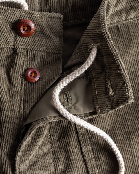 Close-up of Classic Corduroy Shorts - Olive, showing their unique olive corduroy texture, detailed stitching, drawcord waist with two brown buttons, and a white braided drawstring.