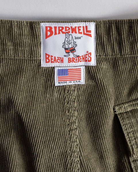 A close-up of the Classic Corduroy Shorts - Olive highlights their SurfNyl fly, “BIRDWELL BEACH BRITCHES” and cartoon bird label, plus a U.S. flag and “MADE IN U.S.A.” tag for classic style and quality.