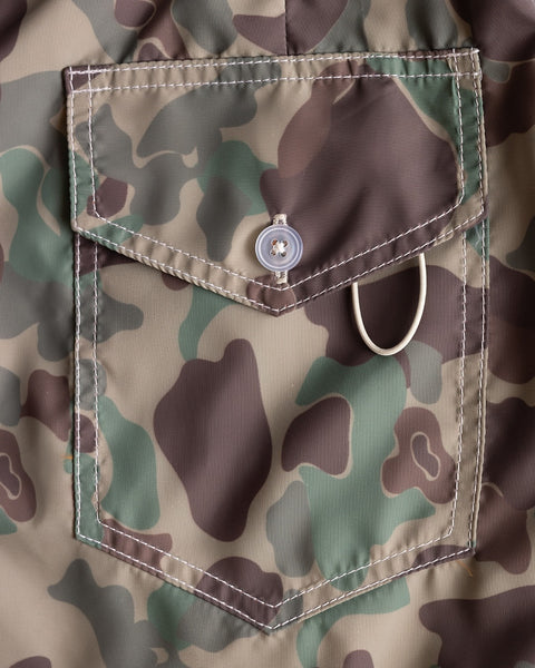 A close-up of the 300 Boardshorts - Frogskin Camo shows a camouflage pocket with a button closure and metal ring, featuring green, brown, and beige blotches.