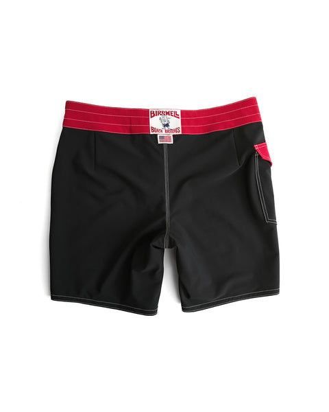 The 808 Mono Stripe - Black/Red boardshorts feature a wide red waistband, white stitching, a small red side pocket, and the Birdwell Beach Britches label. Medium length and proudly made in the USA.
