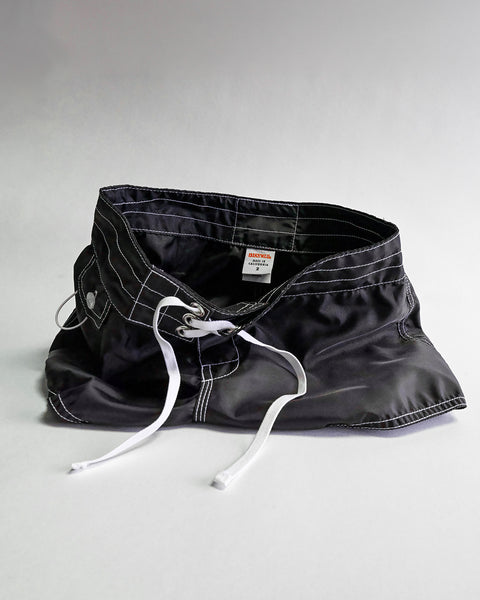 The 400 Boardshorts - Black, featuring white stitching and a white drawstring, are displayed upright like an open mouth against a plain light background.