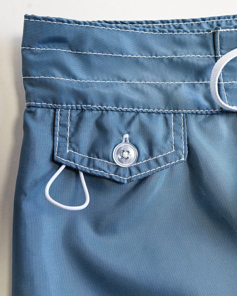 Close-up of the upper section of 400 Boardshorts - Federal Blue, made in USA, showing a small buttoned pocket with white stitching and a white drawstring loop to the left of the pocket.