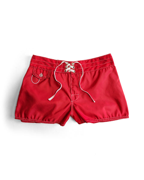 The 400 Boardshorts - Red are quick-drying boardshorts with a lace-up front closure and a small buttoned pocket on the left side, shown on a white background.