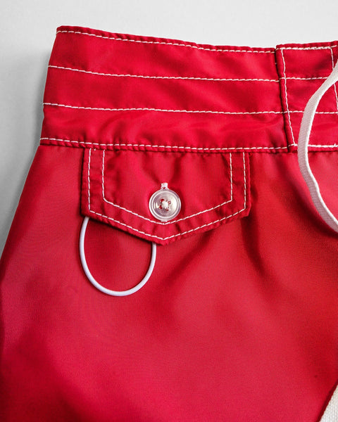 Close-up of the waistband and pocket of the 400 Boardshorts - Red, featuring white stitching, a clear button on the flap, and a white drawstring on the right side. Proudly made in USA.