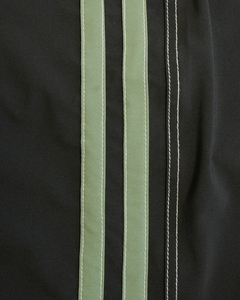 A close-up of 808 Racing Stripes - Black/Olive boardshort fabric, showing two wide vertical olive stripes and a narrow white stripe, each with visible stitching.