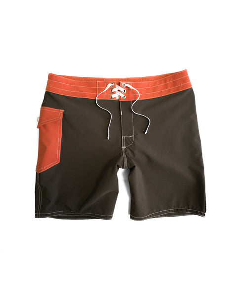 The 808 Pop Pocket - Brown/Paprika are classic-inspired boardshorts made in the USA, featuring a brown body, paprika (orange) waistband, white drawstring, and paprika side pocket—shown on a white background.