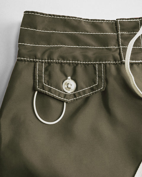 Close-up of an olive green pocket with white stitching, a silver button, and a white drawstring loop highlights the quality details of the 400 Boardshorts - Dark Olive—designed for women's quick-drying comfort at the beach.