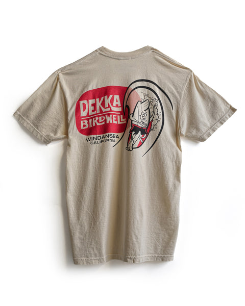 The Birdwell x Dekka T-Shirt - Ivory is garment-dyed 100% cotton, featuring a red and white back graphic of a surfing cartoon pig inside a wave with 