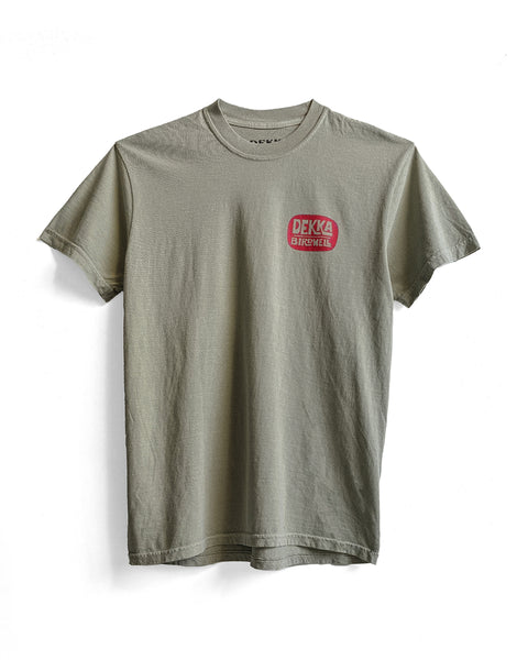 The Birdwell x Dekka T-Shirt - Sandstone is a light gray 100% cotton tee featuring a small red DEKA BIKEHILL logo on the left chest, shown on a white background.