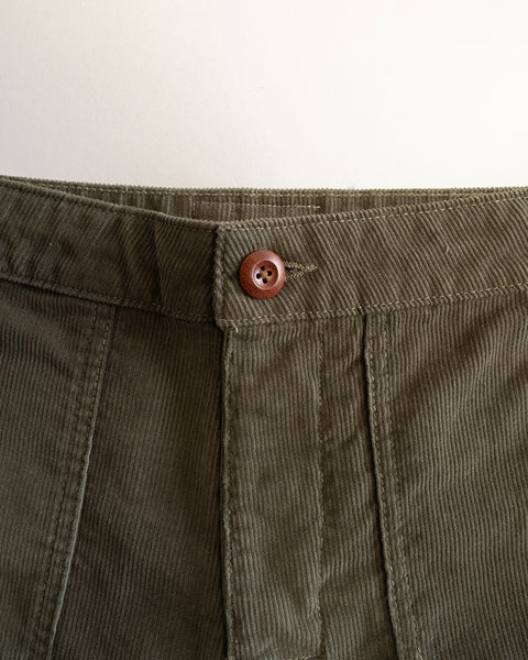 Close-up of the Classic Corduroy Pants - Dark Olive waistband, featuring a brown button and visible stitching, set against a plain white background. These pants are made in Southern California and showcase exceptional craftsmanship and timeless style.