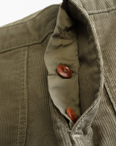 Close-up of the inside of Classic Corduroy Pants in Dark Olive, showing the seam and two brown buttons on a light-colored fabric lining—crafted with the quality you’d expect from our Classic Corduroy Pants, proudly made in Southern California.