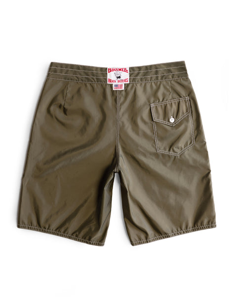 The 312 Boardshorts in Dark Olive are shown from the back, featuring a single buttoned pocket on the right side and a white label with red text above the waistband. These long-length boardshorts are made in the USA from lightweight SurfNyl fabric with a subtle sheen.