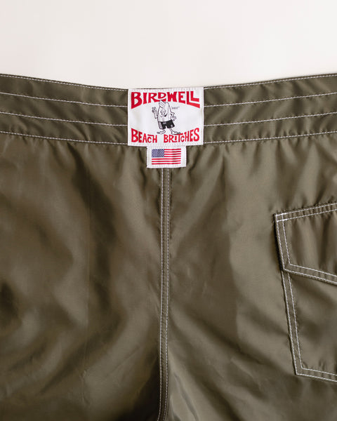 Close-up of the waistband and back pocket of the Dark Olive 312 Boardshorts, featuring Birdwell’s signature patch and a small American flag label—a classic SurfNyl boardshort style, proudly made in the USA.