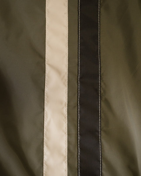 Close-up of the fabric from the Racing Jacket 26 in Dark Olive, Bone, and Black. Reminiscent of classic Birdwell Racing Jacket designs, the material appears smooth, with vertical stripes and visible stitching along the edges.