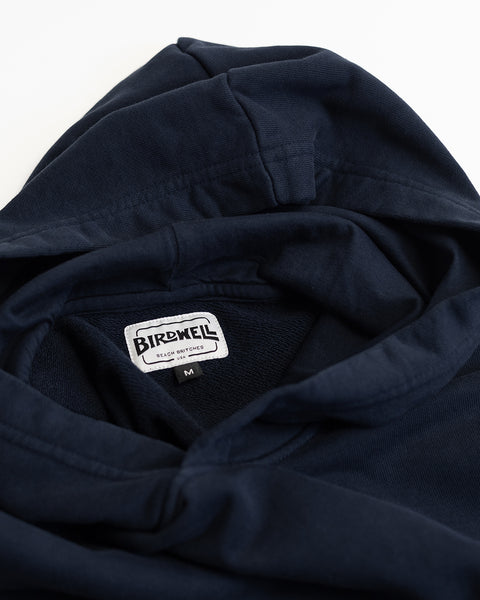 A close-up of the Harmony Hoodie - Navy, crafted from soft French terry, showcasing a visible Birdwell brand tag and a size M label inside the collar area. Made in USA.