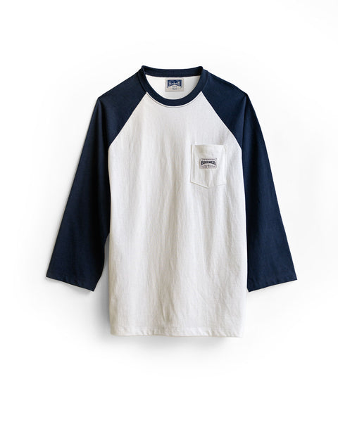 Introducing the Special Teez Pastime in Vintage White/Navy—a relaxed-fit raglan tee with navy blue three-quarter sleeves, a small chest pocket adorned with a rectangular logo patch, and crafted from soft, USA-grown cotton.