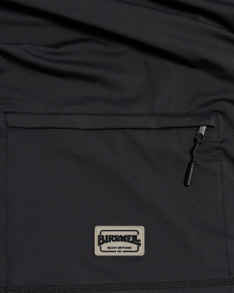 Close-up of the Sunteez Hoodie - Black, featuring a black fabric pocket with a zipper and a rectangular Birdwell Beach Britches USA patch. Made in the USA.