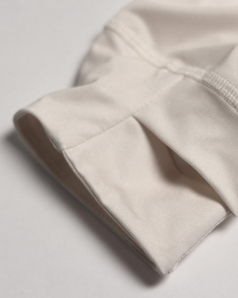 A close-up of the Sunteez Long Sleeve - Bone shows a neatly sewn off-white fabric cuff with visible stitching, crafted from performance stretch fabric for comfort and flexibility, displayed against a plain background.