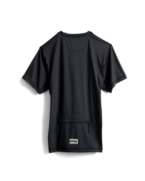 The Sunteez Short Sleeve - Black is laid flat and shown from the back. Made in the USA, it features a small rectangular patch above a zippered pocket near the hem, and is crafted from moisture-wicking fabric for all-day comfort.