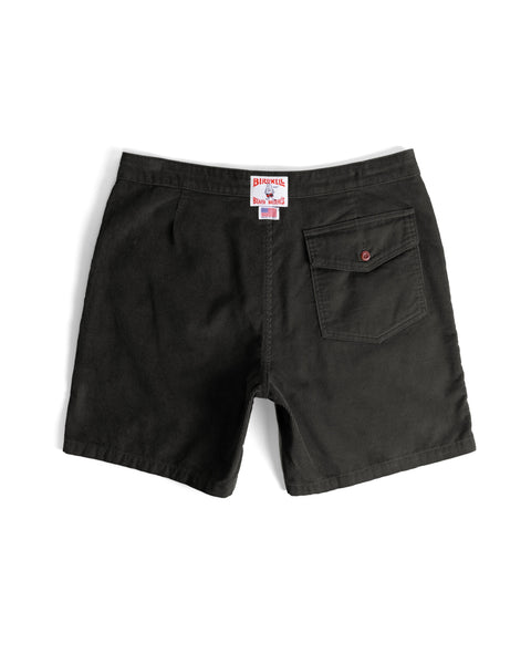 The Classic Corduroy Shorts - Charcoal are shown laid flat with the back facing up. They feature a single buttoned pocket on the right side and a white label with red text sewn onto the waistband above the pocket. Crafted from sturdy corduroy, these casual shorts include an adjustable drawcord waist for comfort.