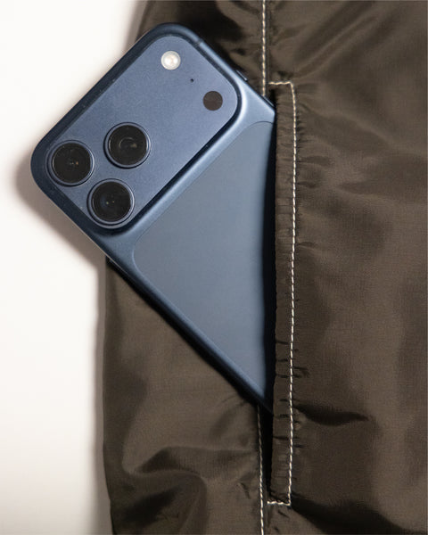 A dark blue smartphone tucked into the pocket of a brown/acorn Capistrano Jacket.