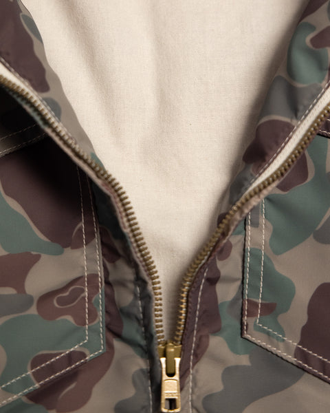 Close-up of a partially unzipped Capistrano Jacket - Frogskin/Acorn in a camouflage print with a tan lining.