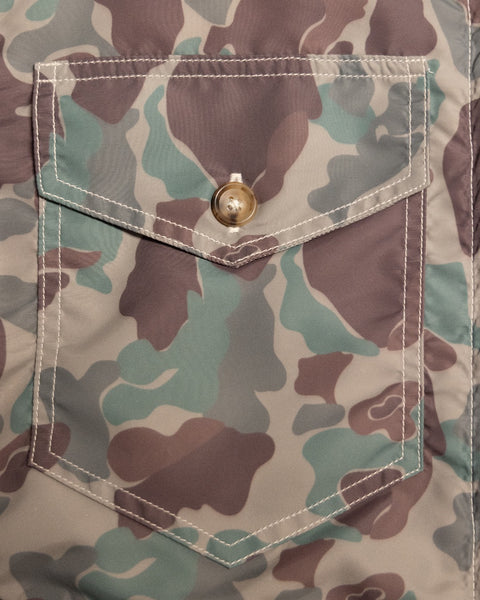 Close-up of a buttoned chest pocket on a Capistrano Jacket - Frogskin/Acorn featuring a green and brown camouflage pattern.
