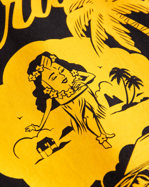 The Daydreamin' Birdie T-Shirt - Black features a bold yellow and black illustration of a woman in a hula skirt with palm trees, a house, and clouds, capturing the classic Birdwell style.