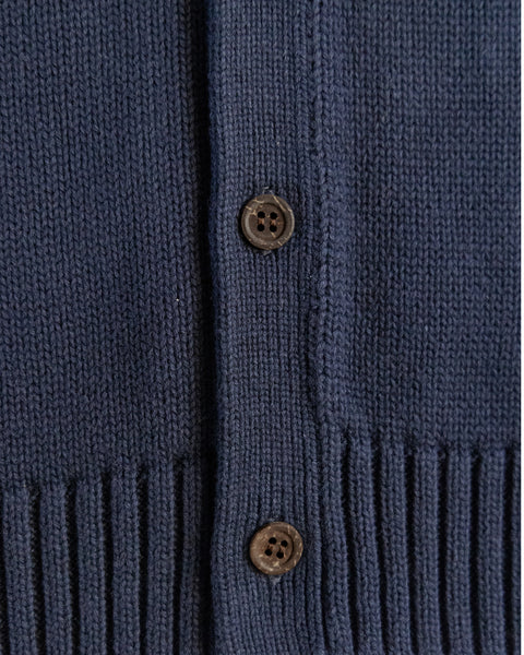 Close-up of the Racing Cardigan Sweater in Navy/Bone, made from 100% cotton, with two brown buttons and ribbed detailing along the bottom edge.