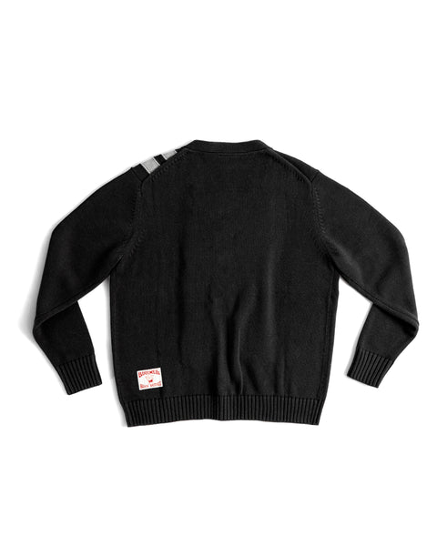 The Racing Cardigan Sweater - Black/Gray in regular fit is shown from the back, featuring two gray stripes on the left shoulder and a rectangular white and red patch near the right bottom hem.