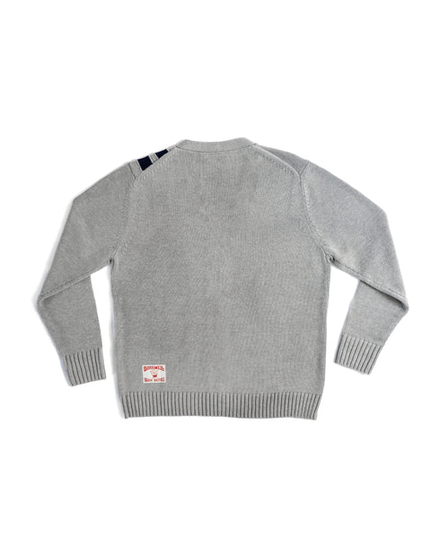 The Racing Cardigan Sweater - Gray/Navy is a light gray cotton blend sweater shown from the back, featuring ribbed cuffs and hem, a white tag with red text by the left hem, and two navy stripes on the right shoulder.