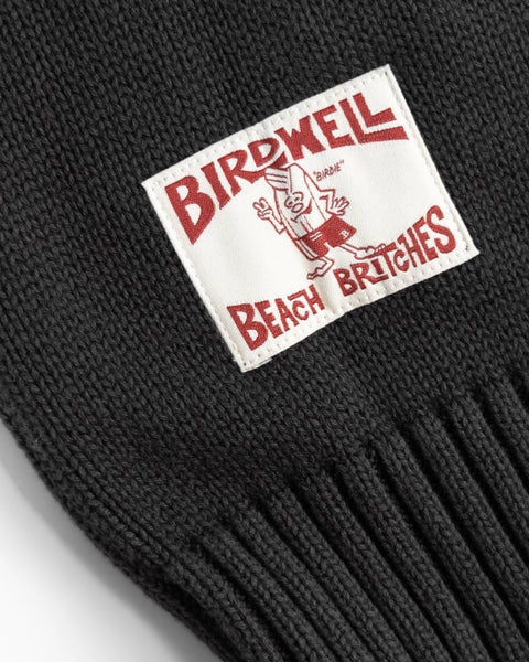 A close-up of the Comp Zip Sweater - Black/Gray shows a white patch with red 