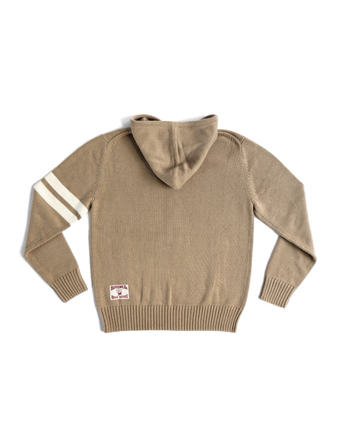 The Comp Zip Sweater - Bark/Bone is a light brown midweight knit seen from the back, with two white stripes on the left sleeve and a rectangular patch near the bottom hem.